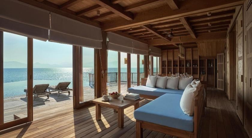 Phòng khách villa nhìn ra biển với sofa gỗ, bàn trà và rèm